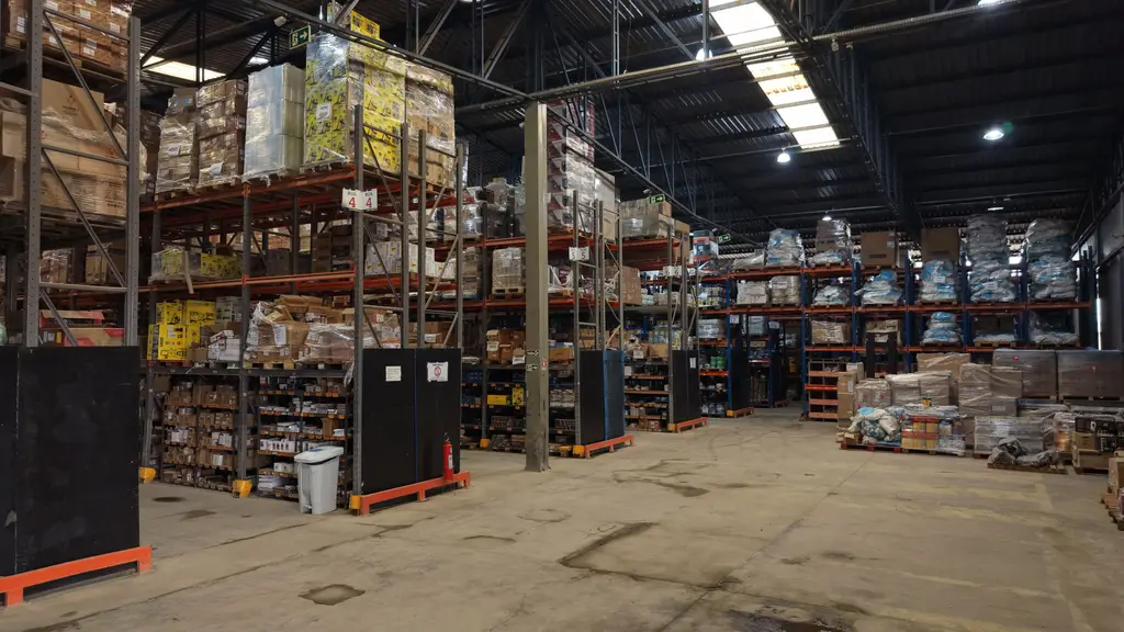 Interior do centro de distribuição da Master, com porta-paletes de vários andares cheios de material e paletes no chão